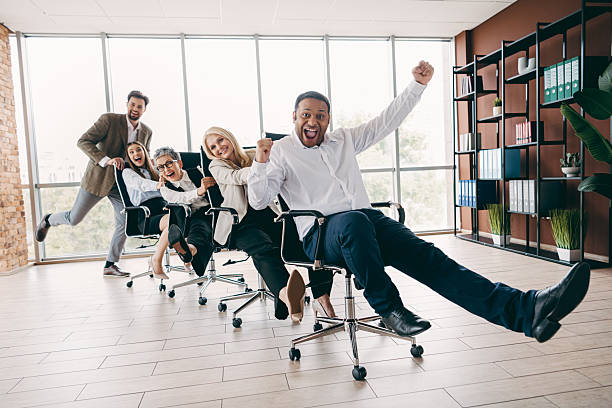 istock Energetic team having fun racing office chairs in a bright modern workplace, showcasing teamwork 2237271205