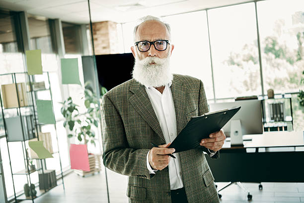 istock Confident senior businessman holding clipboard at modern office workspace showcasing professionalism and expertise 2237272152