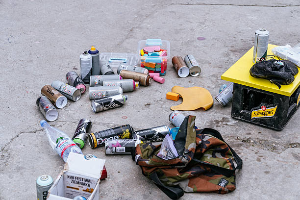 Stocznia, Gdańsk - Used spray paint cans, gloves, and assorted equipment lying on the ground, showing remains of artistic or creative graffiti activity in 100cznia urban space.