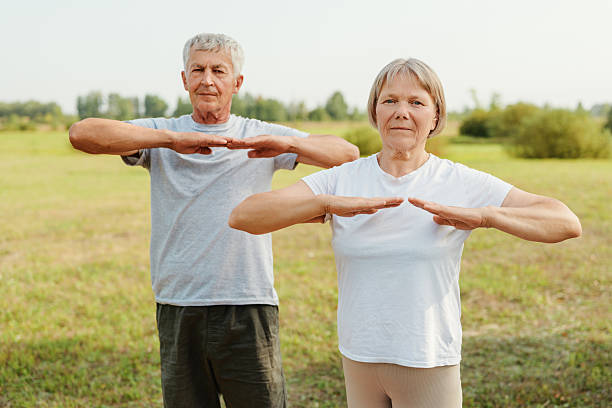 istock Active senior couple standing in a field and doing a horizontal arm stretch, representing their healthy lifestyle. 2237276992