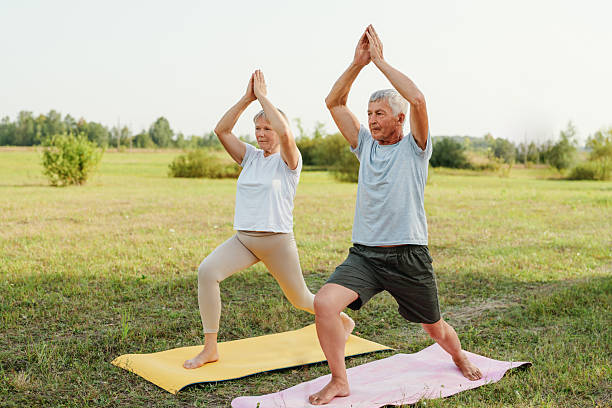 istock Active senior couple doing the warrior pose on yoga mats in a field. 2237276995
