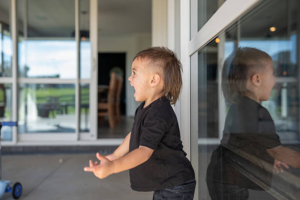 Beautiful twin sisters are playing in domestic room, making a faces on window.