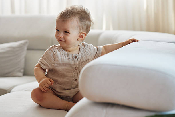 istock Cheerful baby boy sitting on modern sofa at home 2237286724
