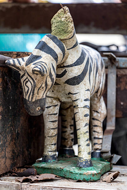 The damaged statue of zebra with a falling head, close up.
