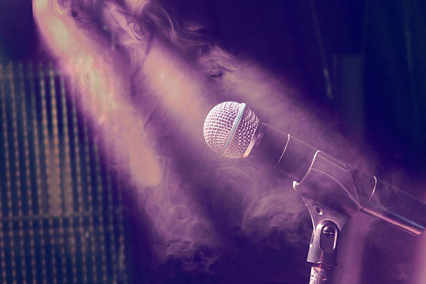 istock Microphone on stage, illuminated by colored lights, with the vibrant atmosphere of a pop rock concert. 2237287362