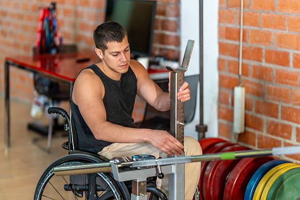 istock Man in wheelchair adjusting equipment for weightlifting workout 2237290311
