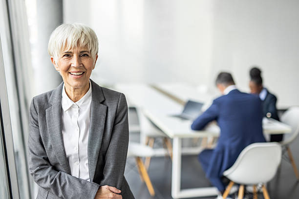 istock Senior businesswoman smiling confidentially while colleagues working in background 2237290445
