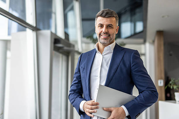 istock Confident businessman standing with laptop inside modern office 2237290522