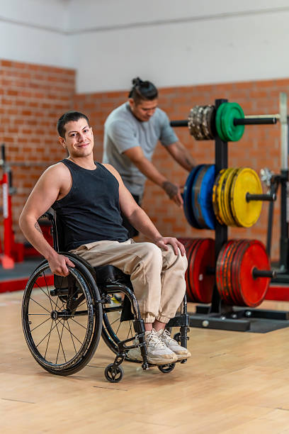 istock Disabled man in wheelchair exercising with trainer at gym 2237290592