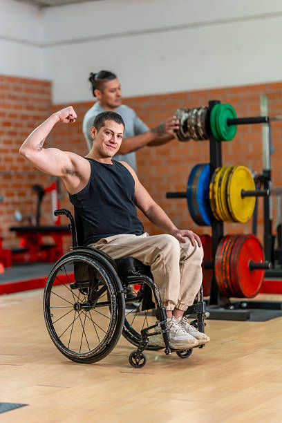 istock Man in wheelchair flexing bicep at gym 2237290598