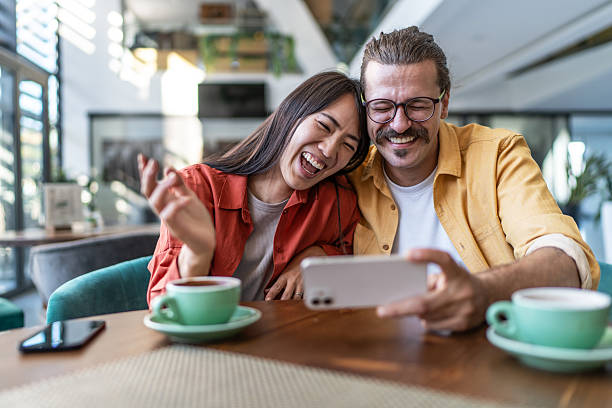 istock Happy multiracial couple laughing watching smartphone in cafe 2237292278