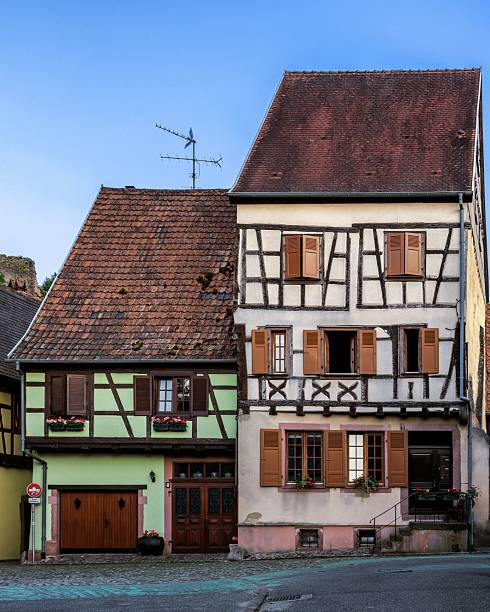 Charming half-timbered houses with colorful facades in a quaint European village under a clear blue sky.
