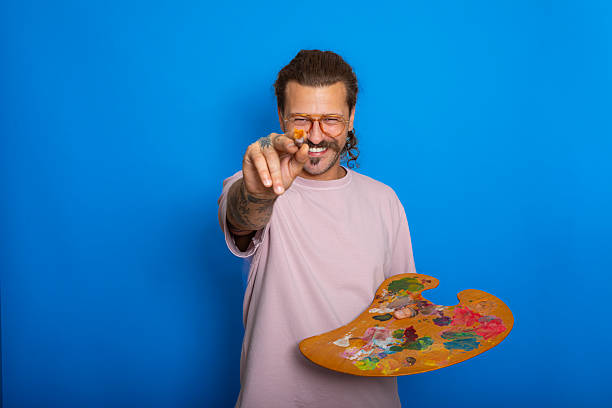 Man holding paint palette and brush against blue background