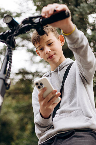 istock Teen boy outdoors riding an electric scooter while using a smartphone. 2237295745