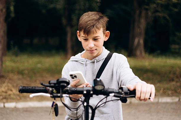 istock Teen boy outdoors riding an electric scooter while using a smartphone. 2237295757