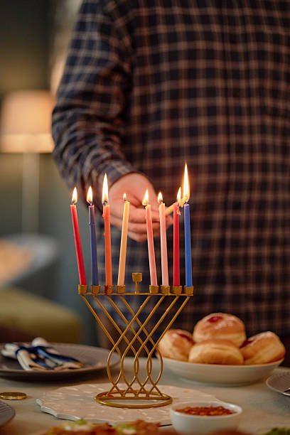 istock Man Lighting Menorah Candles Celebrating Hanukkah 2237296112