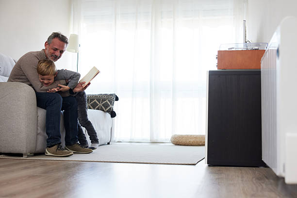 istock At home, a father gets distracted by his son while reading a book. 2237297249