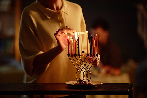 istock Woman Lighting Hanukkah Menorah Candles during Celebration 2237298266