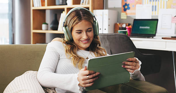 istock Remote work from home, tablet and woman on sofa, headphones and creativity with content creation. Person, apartment or freelancer on couch, tech and smile with subscription, app or online streaming 2237303628