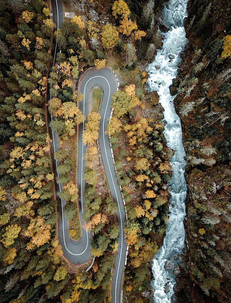 istock Curvy road in autumn forest with river 2237305989