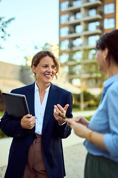 istock Professional Woman In Navy Blazer Engages Colleague Outdoors While Carrying Tablet 2237310762