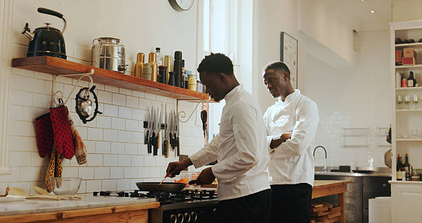 Cooking class, instructions and process with black men in kitchen of home for culinary course. Food, learning and study with chef teaching student in apartment for lesson or skills development