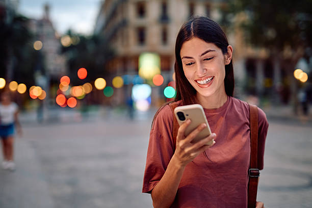 istock Young woman smiling using phone in city at night 2237315584