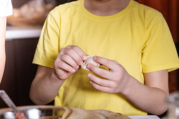 istock Kid boy make meat dumplings ravioli pelmeni in the kitchen 2237316869