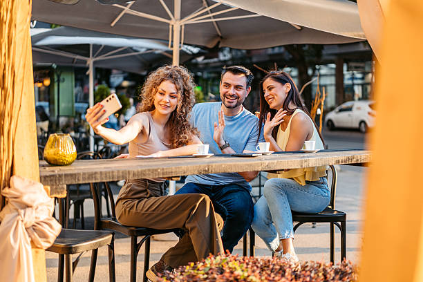 istock A Small Group Of Friends Having A Video Call Using Phone While Drinking Coffee In A Sidewalk Café Outdoors 2237323907