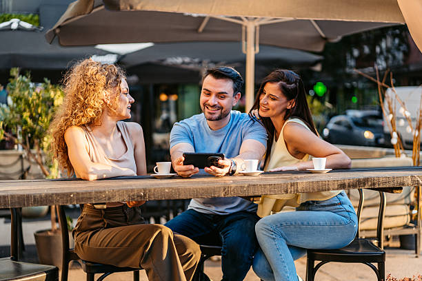 istock A Small Group Of Friends Watching Something On The Phone While Drinking Coffee In A Sidewalk Café Outdoors 2237324067