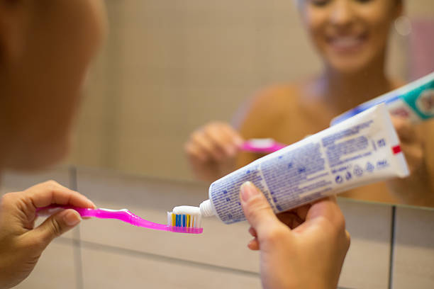 Beautiful young smiling woman brushing teeth in the bathroom