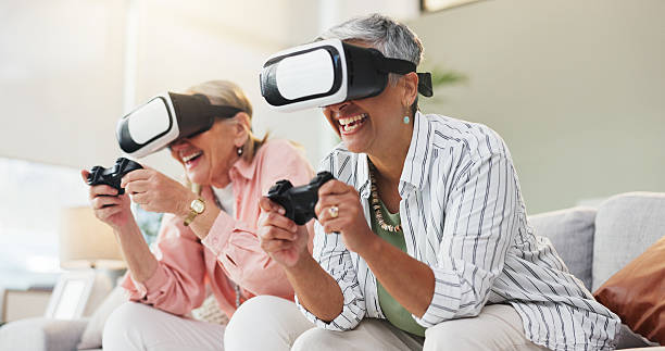 istock VR, video game and senior women on sofa with 3d technology, controller and fun in living room. Happy, friends and female people on couch in home with gaming console, virtual reality or AI simulation 2237324820