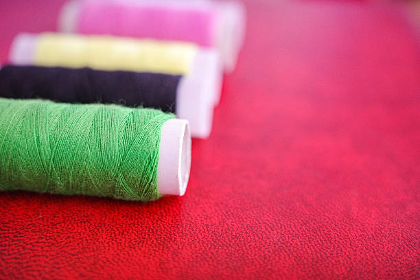 Close-up of colorful spools of sewing thread arranged on a red surface. Creative composition symbolizing arts, crafts, creativity and handmade design