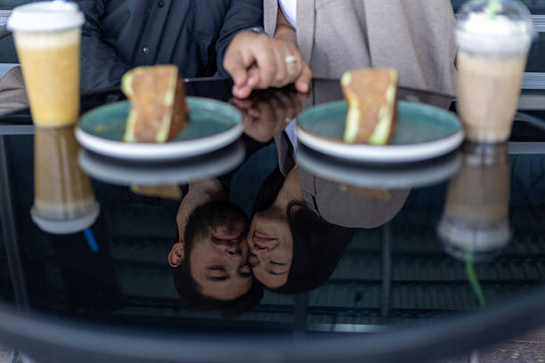 A person's hand reaches for a piece of cake on a table, with another cake and tw