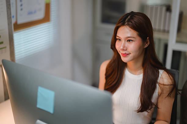 istock Female business professional smiling, working on computer in office setting, staying focused on her tasks and goals 2237328290