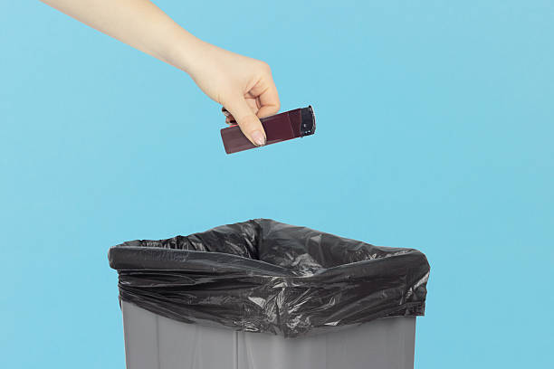 istock throw the lighter in the trash, outstretched hand with a lighter in front of the trash can, the concept of the dangers of smoking cigarettes, quitting smoking 2237330029