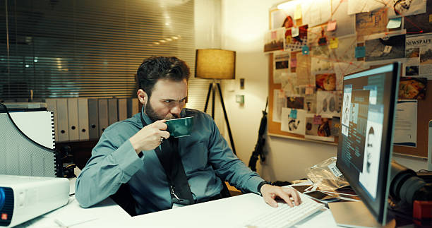 istock Coffee, computer screen and investigation with police man in office at night for case or justice. Drink, evidence and thinking with detective at desk in workplace for review of crime search clues 2237334499