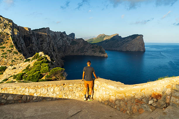 Rear view of a man on a cliff enjoying the sea view in the morning, Mallorca Island, Balearic Islands, Spain