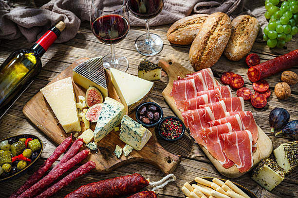 istock High angle view of a cheese board and cold cuts table. Mediterranean appetizer on rustic table. Spanish tapas or antipasto. Tasty food for snack or party. Cured ham, chorizo or cold cuts with red wine 2237342126