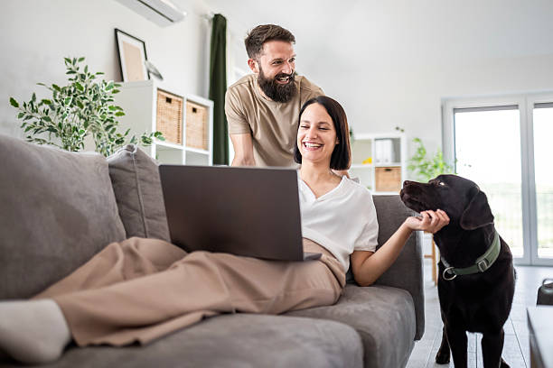 istock Couple Relaxing on Sofa with Laptop and Beloved Pet 2237347980