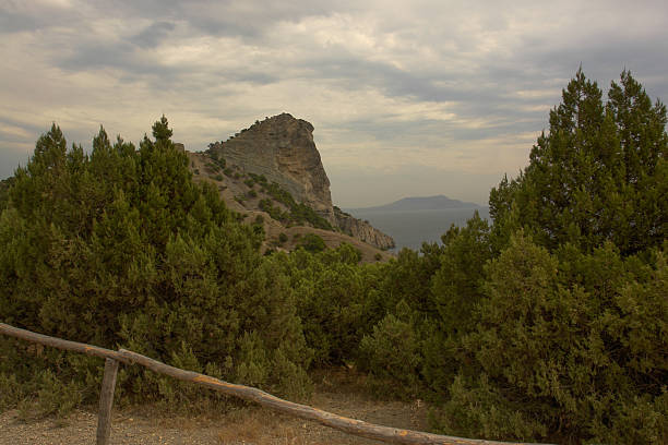 Scenic view of Cape Kapchik in Crimea with rocky cliffs and sea horizon under blue sky.