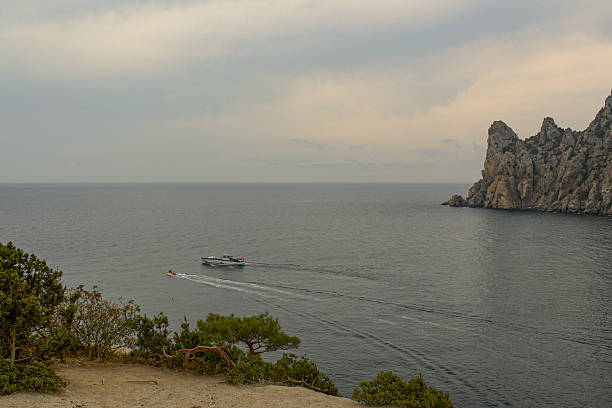 Scenic view of Cape Kapchik in Crimea with rocky cliffs and sea horizon under blue sky.