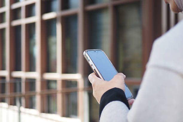 istock Person using smartphone while standing near modern building exterior 2237354781