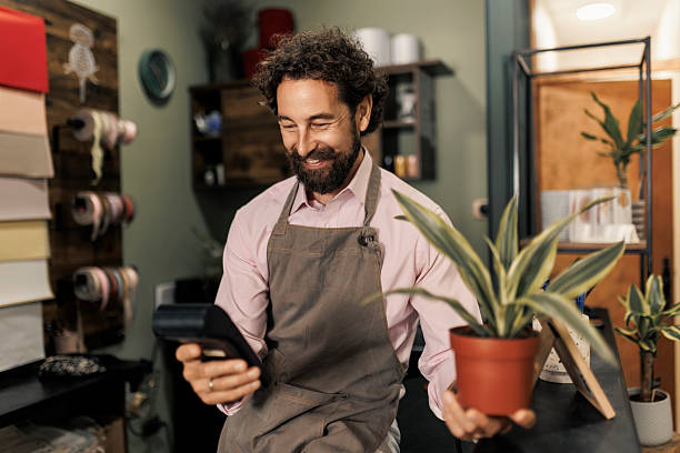 istock Florist handing potted plant to customer and processing payment with POS terminal 2237354789