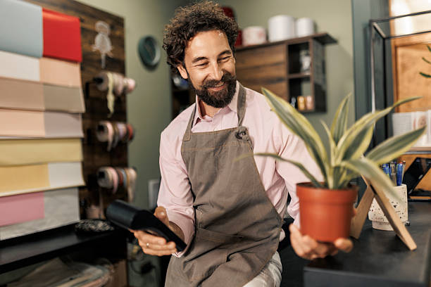 istock Florist handing potted plant to customer and processing payment with POS terminal 2237356302