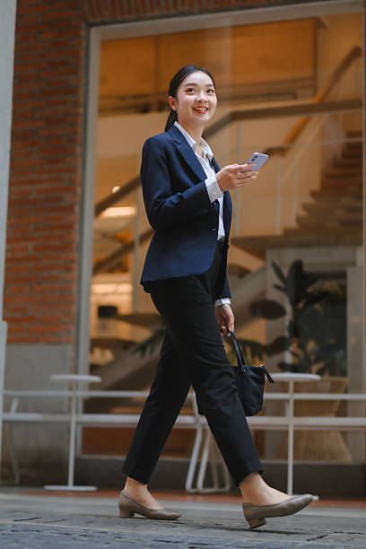 Business woman walking urban street using smartphone
