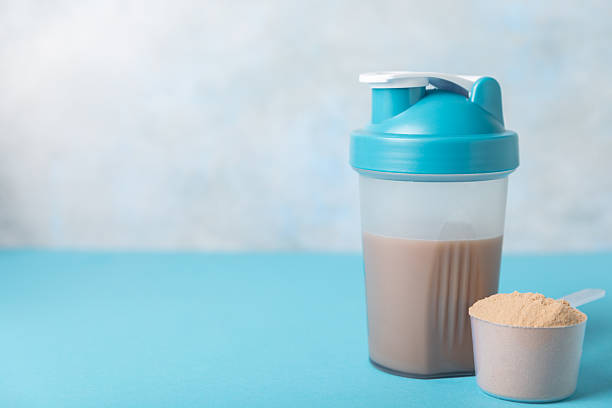 istock Protein shake with protein powder on a colored background. The powder is mixed with water or milk. A dietary supplement for a balanced diet. Whey protein. Fitness and gym diet nutrition. 2237356949