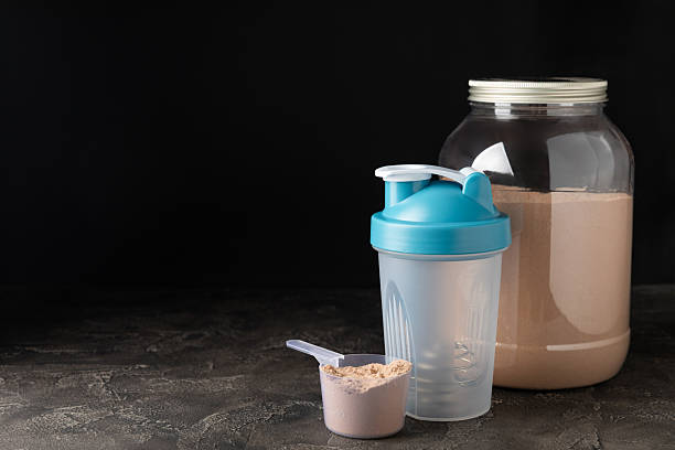 istock Protein shake with protein powder on a colored background. The powder is mixed with water or milk. A dietary supplement for a balanced diet. Whey protein. Fitness and gym diet nutrition. 2237357041