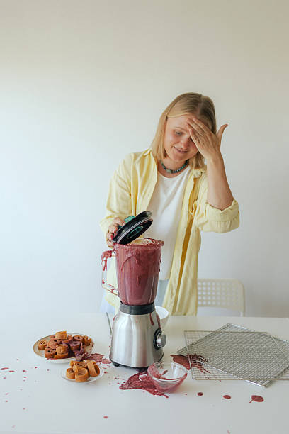 istock Close-up of a woman in her kitchen whose blender broke while making homemade fruit puree. The malfunction splattered fruit everywhere, leaving her surrounded by a messy scene instead of a healthy snack. 2237362917