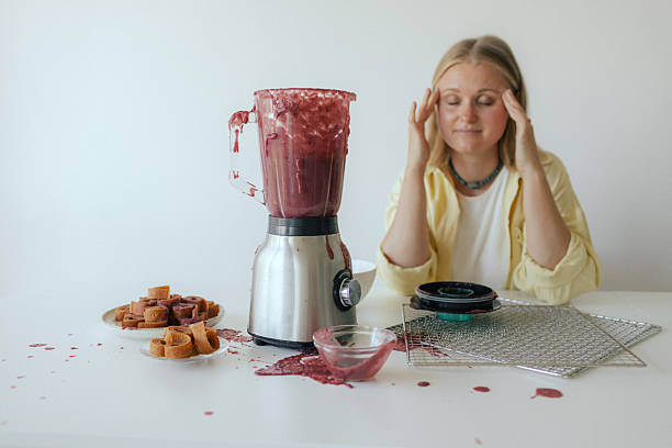 istock Close-up of a woman in her kitchen whose blender broke while making homemade fruit puree. The malfunction splattered fruit everywhere, leaving her surrounded by a messy scene instead of a healthy snack. 2237363189